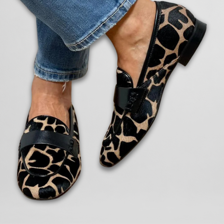 Black and leopard print loafers worn with cuffed blue jeans, front view
