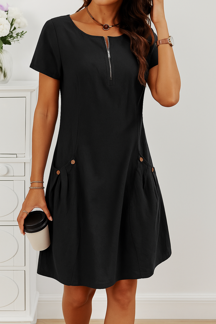 Front view of a model wearing the black Millie summery dress with zip detail and decorative buttons on pockets