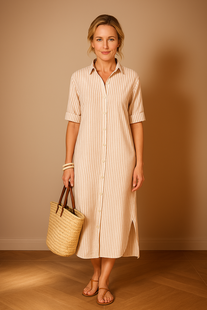 Front view, model wearing a striped shirt dress with rolled sleeves, holding a straw bag and wearing sandals