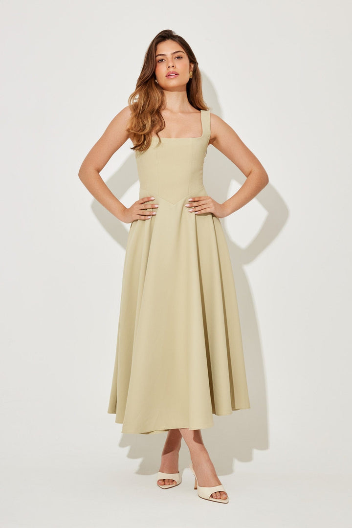 Front view of a model wearing a sand timeless flowy midi dress with a square neckline and a high waist