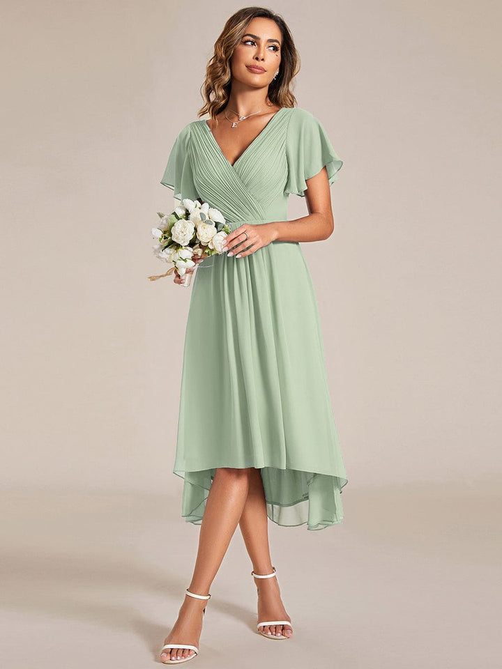 Front view, model wearing a mint green chiffon V neck evening dress with flutter sleeves and a high low hem
