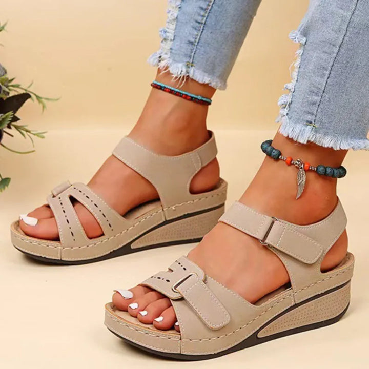 Front view, a pair of beige arch-support wedge sandals with hook and loop straps on a model&