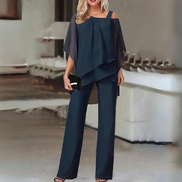 Front view, elegant straight-leg trousers and flowing top set in deep teal worn by model with black clutch and heels