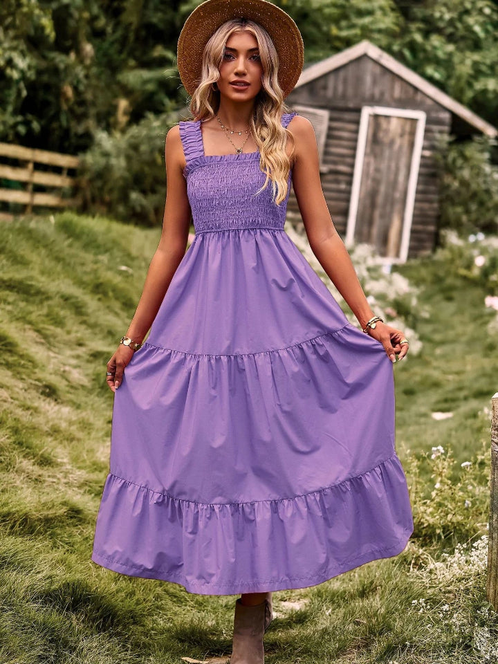 Front view of a model wearing a purple sleeveless halter maxi dress with a square neckline and tiered skirt