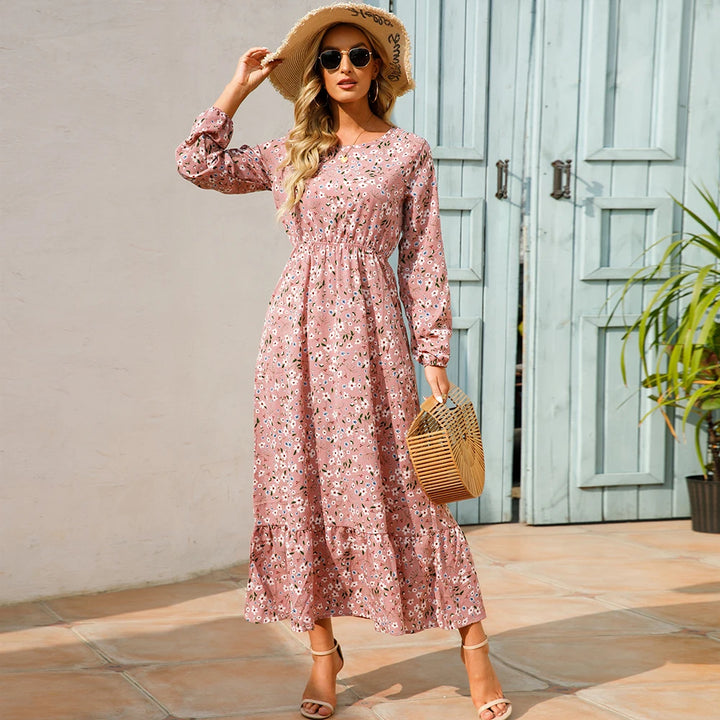 Front view, worn by model, a bohemian chiffon maxi dress in pink with white floral print, straw hat, and sunglasses