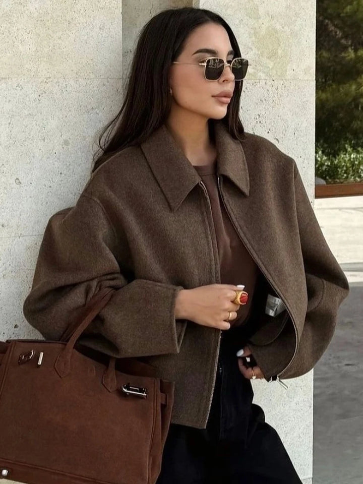 Front view, model wearing a brown Vivienne woolen zip-up jacket with a matching top, black pants, and sunglasses