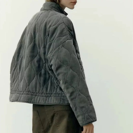 Back three quarter view of a grey women's vintage quilted cotton jacket worn by model