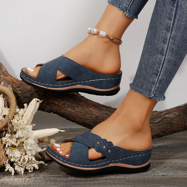 Worn by model, a pair of navy blue Gabrielle Summer Slides with perforated straps and white stitching detail