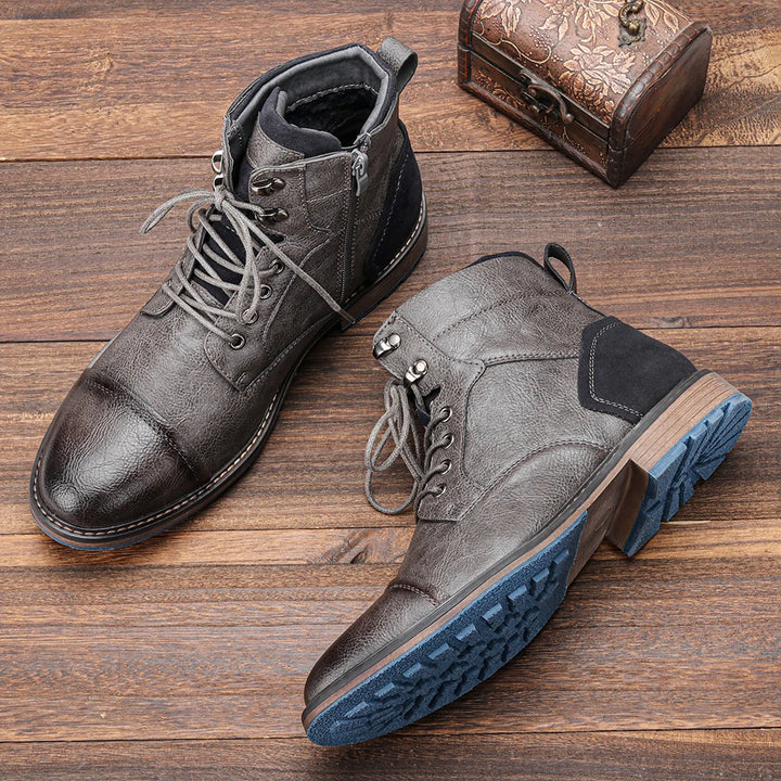 Top view of two grey leather ankle boots with blue soles, laces, and a side zip closure