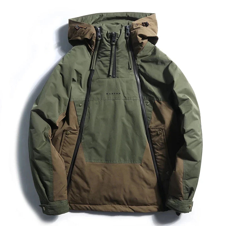 Front view of a khaki and olive bold colour block techwear jacket with a half zip and hood
