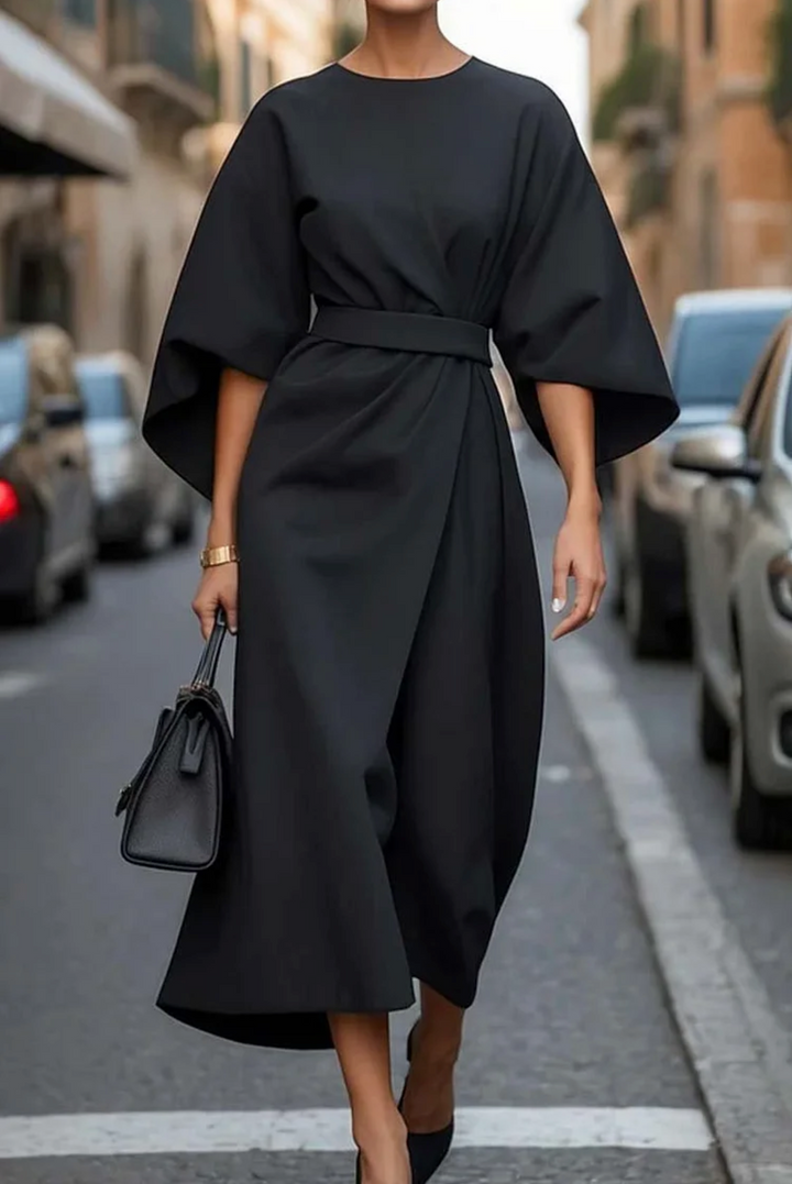 Front view of a model in a black elegant knee-length dress with wide lantern sleeves and a wrap skirt design