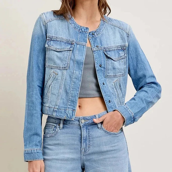 Front view of a model wearing a light blue denim jacket with utility pockets over a grey crop top