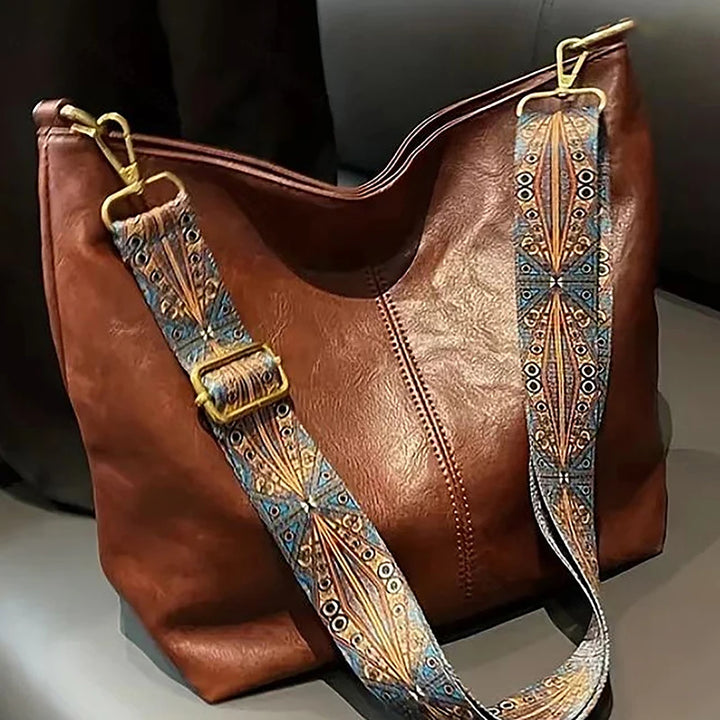 Front view of a brown PU leather vintage bucket shoulder bag with a patterned strap