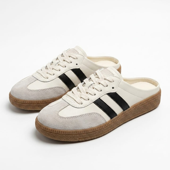 Three quarter view of two casual platform slip-on mules with beige uppers, black stripes and a patchwork design