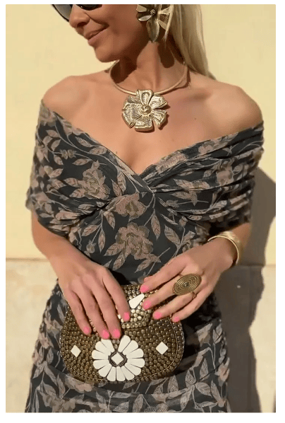 Front view, worn by model, of the Christi Off-Shoulder V-Neck Printed Dress with a gold flower necklace and clutch