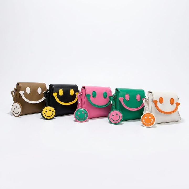 Front view of five Bright Smile crossbody bags in brown, black, pink, green, and white with matching keyrings