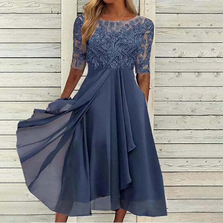 Front view of a model wearing a blue lace dress with sheer sleeves and a flowing viscose skirt
