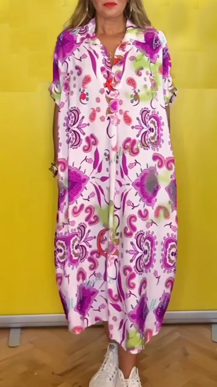 Front view of a model wearing a loose elegant floral dress with a collared neckline and short cuffed sleeves