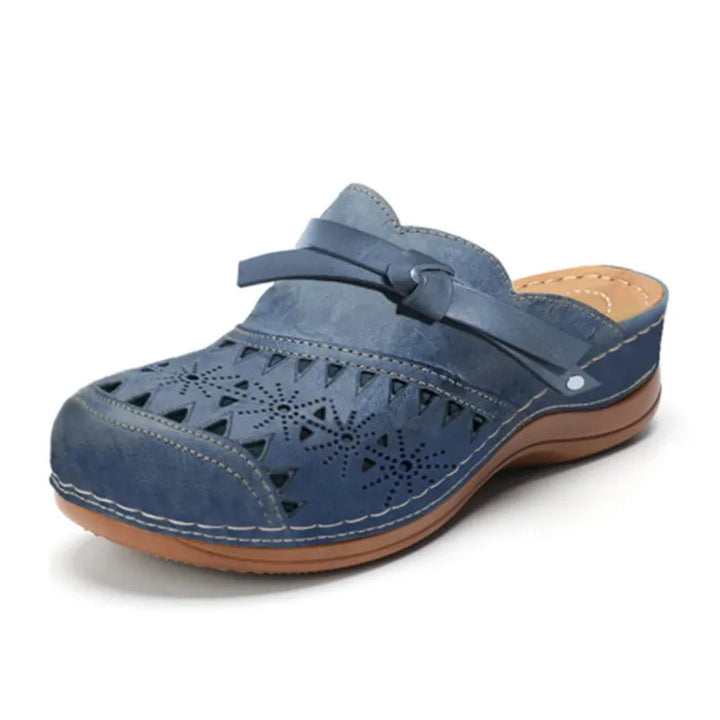 Blue wedge heel slip-on sandals, three quarter view, with decorative cut-outs and a small knotted strap