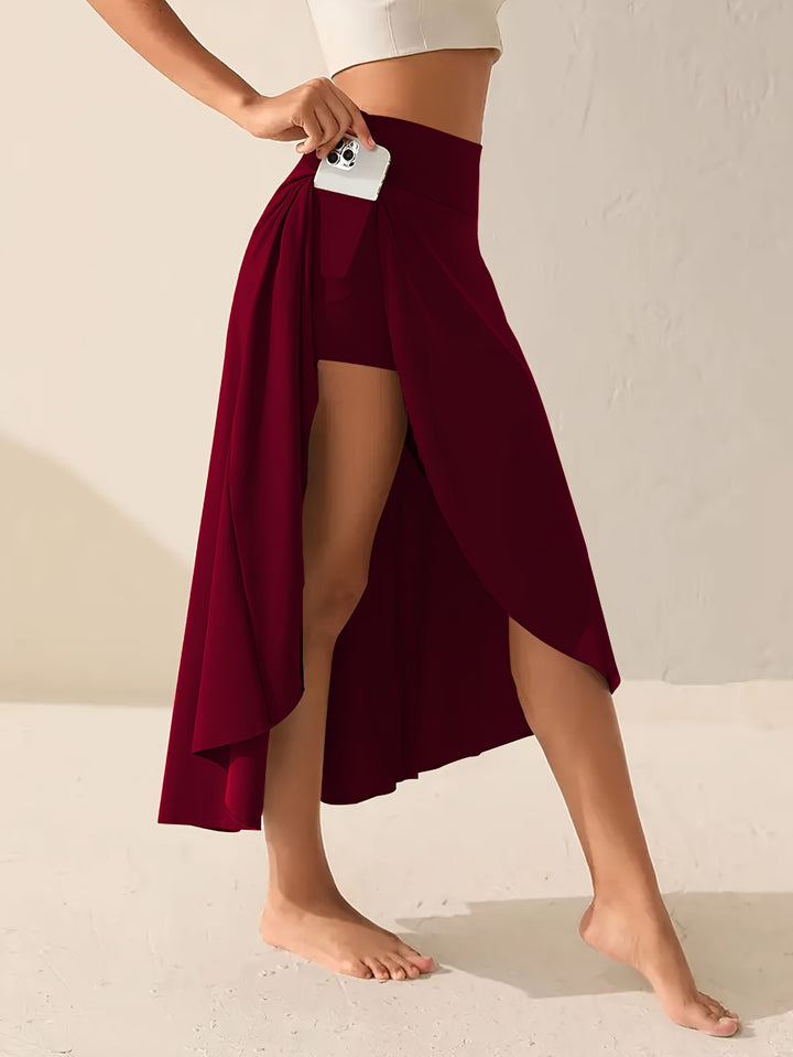 Side view, model wearing a high-stretch asymmetric sports skirt with phone in side pocket