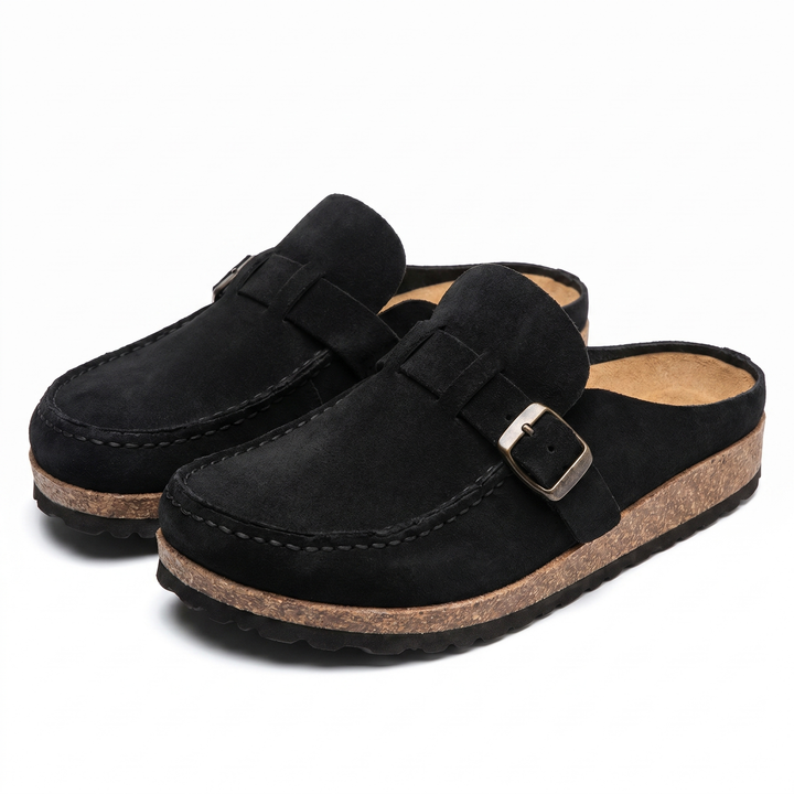 Three quarter view of black suede loafers with buckle and stitching detail on the upper and cork-like soles