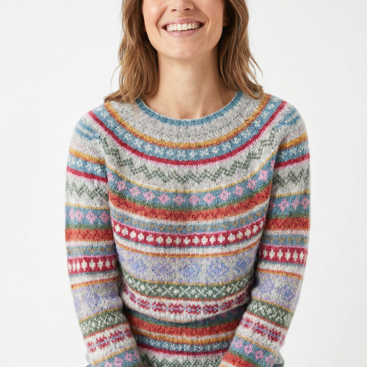 Front view of a woman wearing a retro Nordic knit jumper with colourful patterns and a wide smile