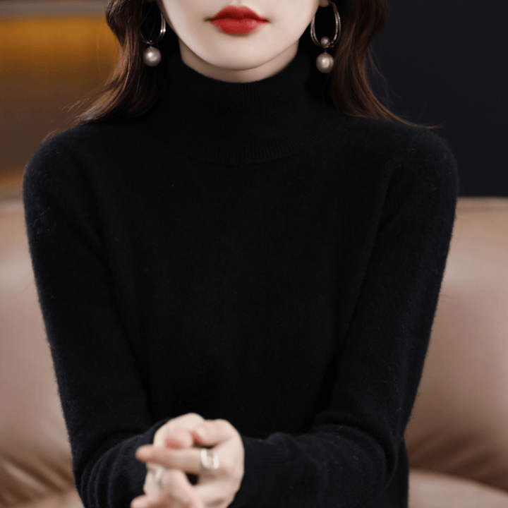 Front view of a woman wearing a black 100% cashmere turtleneck jumper with pearl earrings and a silver ring