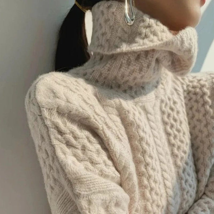 Close up of a model wearing a cream cashmere cable knit turtleneck sweater with a silver earring