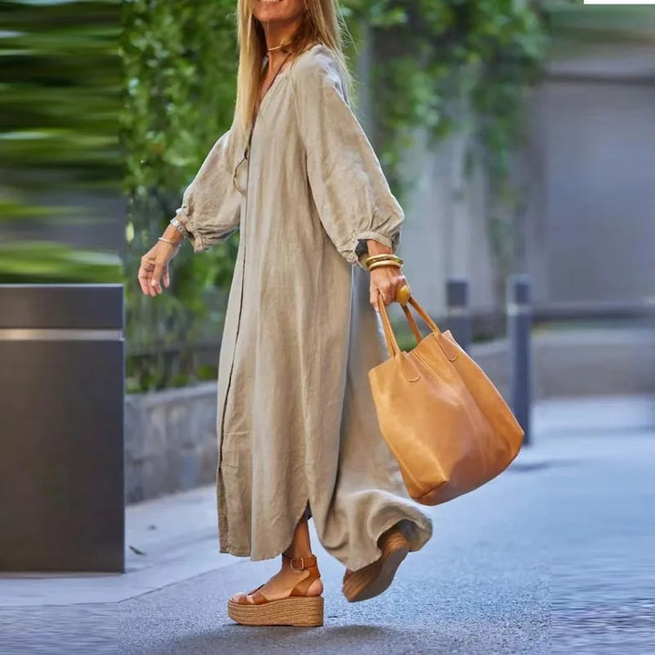 Side view, model walking in a retro loose maxi dress with long sleeves and a tan handbag