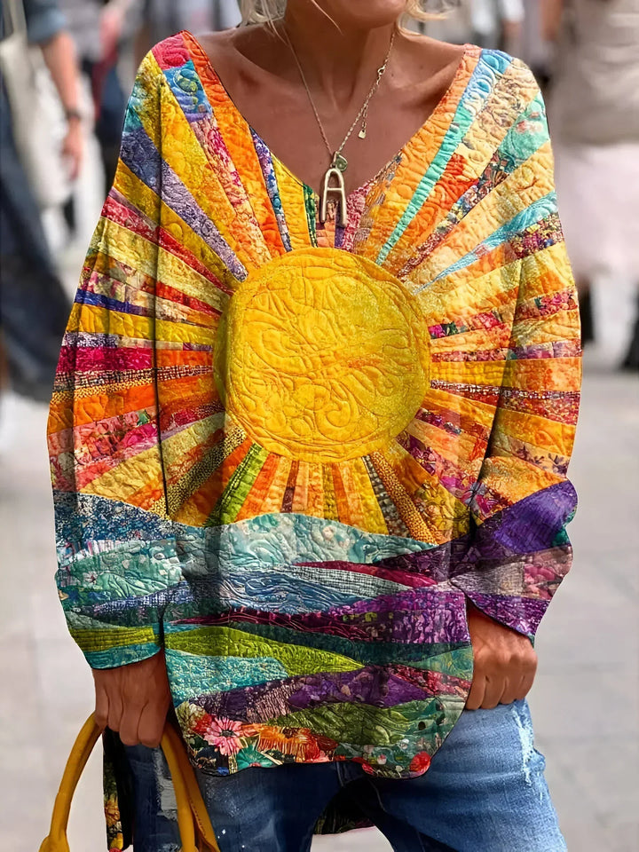 Front view of a woman wearing the premium fabric blouse with a sun and landscape quilt pattern, paired with jeans