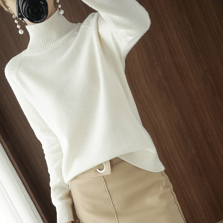 Front view of a model wearing the cream turtleneck jumper with a beige skirt and pearl earrings